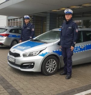 Policjanci stojący przy radiowozie oznakowanym