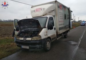 Samochód typu Bus z otwartą pokrywą silnika. Za nim stoi zaparkowany radiowóz