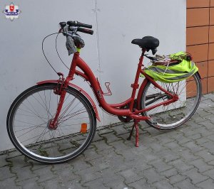 Rower koloru czerwonego oparty o szarą ścianę