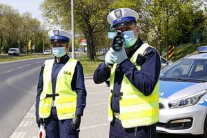 Policjanci w kamizelach odblaskowych dokonujący pomiaru prękości