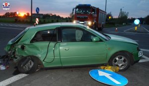 Uszkodzony samochód stoi na wysepce wyłączonej z ruchu. Za nim wóz Straży Pożarnej