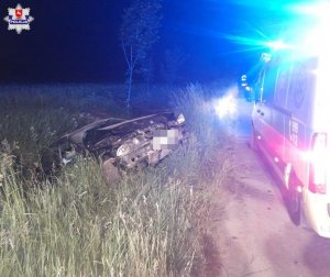 Samochód marki BMW stoi w rowie. Przed nim karetka pogotowia z włączonymi światłami błyskowymi