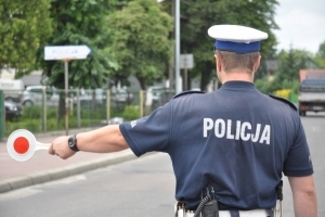 policjant zatrzymuje na ulicy tarczą pojazd