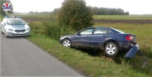 Uszkodzony samochód audi w rowie. Na jezdni stoi oznakowany radiowóz