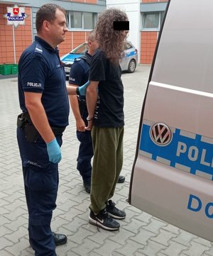 Tymczasowo aresztowany 21-latek umieszczany przez policjantów w radiowozie