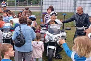 dziecko na motocyklu obok policjant i dzieci