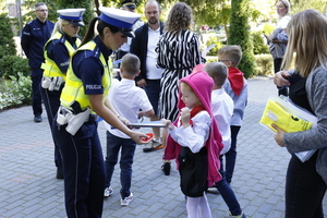 Policjantki rozdają odblaski dzieciom pod szkołą.