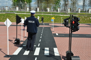 Policjant przeprowadzający konkurencję jazdy rowerem po miasteczku ruchu drogowego