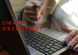 Na tle laptopa dłonie, w których trzymana jest karta bankomatowa