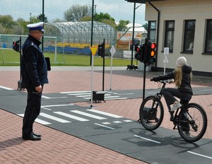 Policjant przeprowadza konkurencję jazdy rowerem po miasteczku ruchu drogowego