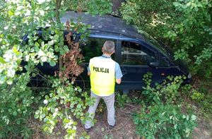 Policjant wykonuje czynności przy samochodzie