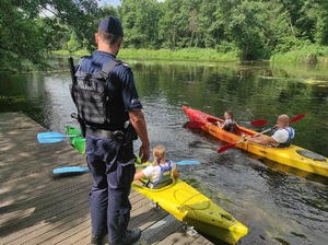 dwaj kajakarze w kajakach, na pomoście policjant