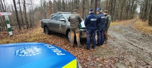 Policjanci i Strażnicy w lesie przy radiowozach służbowych