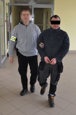 Policjant prowadzi zatrzymanego mężczyznę