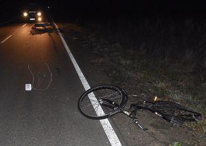 Miejsce wypadku drogowego. Na jezdni leży rower, a za nim motorower. Policjanci zabezpieczają miejsce zdarzenia