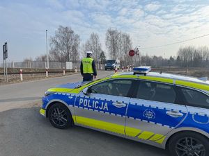 Policjant obserwuje  niestrzeżony przejazd kolejowy