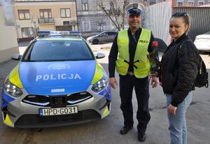 Policjant wręcza kobiecie różę
