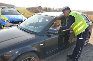 Policjant wręcza kierującej różę
