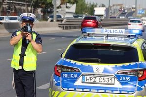 Policjant mierzy prędkość na drodze. Obok radiowóz