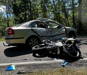 Uszkodzony motocykl leży obok skody