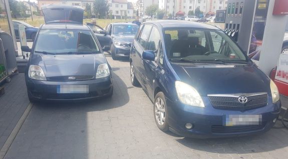 Ford Fiest zaparkowany na stacji paliw. Za nim nieoznakowany radiowóz policyjny