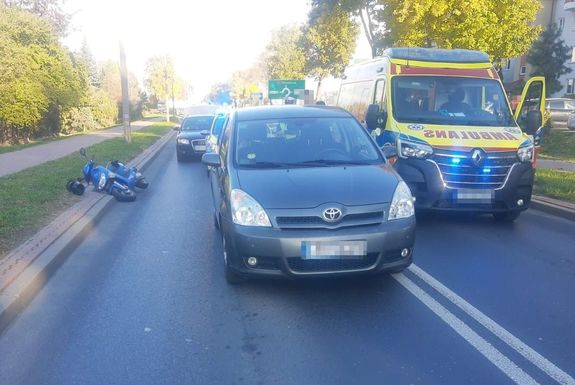 Miejsce wypadku drogowego. Toyota stoi na jezdni, a za nią leży skuter.