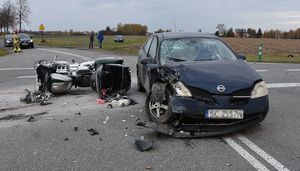 Miejsce wypadku drogowego. Uszkodzyn motocykl i samochód stoją na jezdni