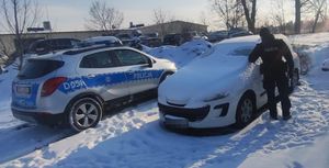 Policjant sprawdza wnętrze zasypanego śniegiem samochodu