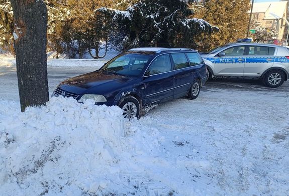 VW Passat stoi w zaspie śniegu, a za nim oznakowany radiowóz