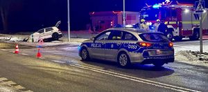 Miejsce zdarzenia drogowego. W rowie znajduje się VW Golf. Oznakowany radiowóz stoi na drodze