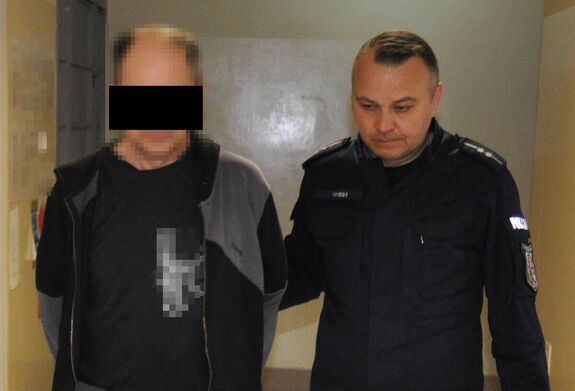 Policjant prowadzi zatrzymanego mężczyznę