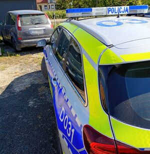 Ford Focus stoi na szutrowym podłożu, a za nim oznakowany radiowóz