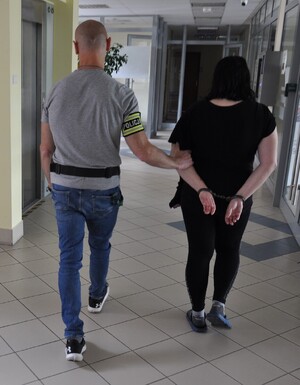 Policjant prowadzi zatrzymaną kobietę