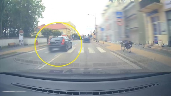 Osobowe auto wyprzedza pod prąd pojazdy na przejściu dla pieszych.