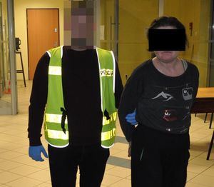 Policjant prowadzi zatrzymaną kobietę